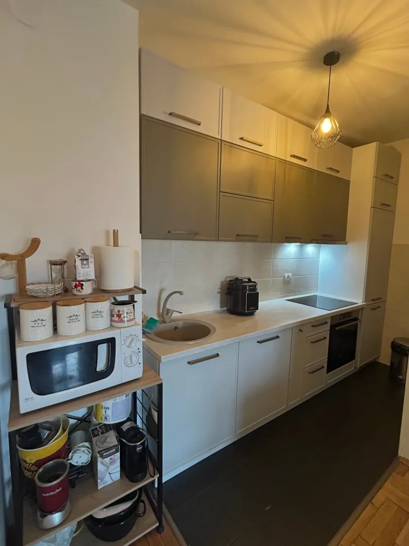 Moderna kuhinja sa bijelim i sivim elementima i ugradnom tehnikom.