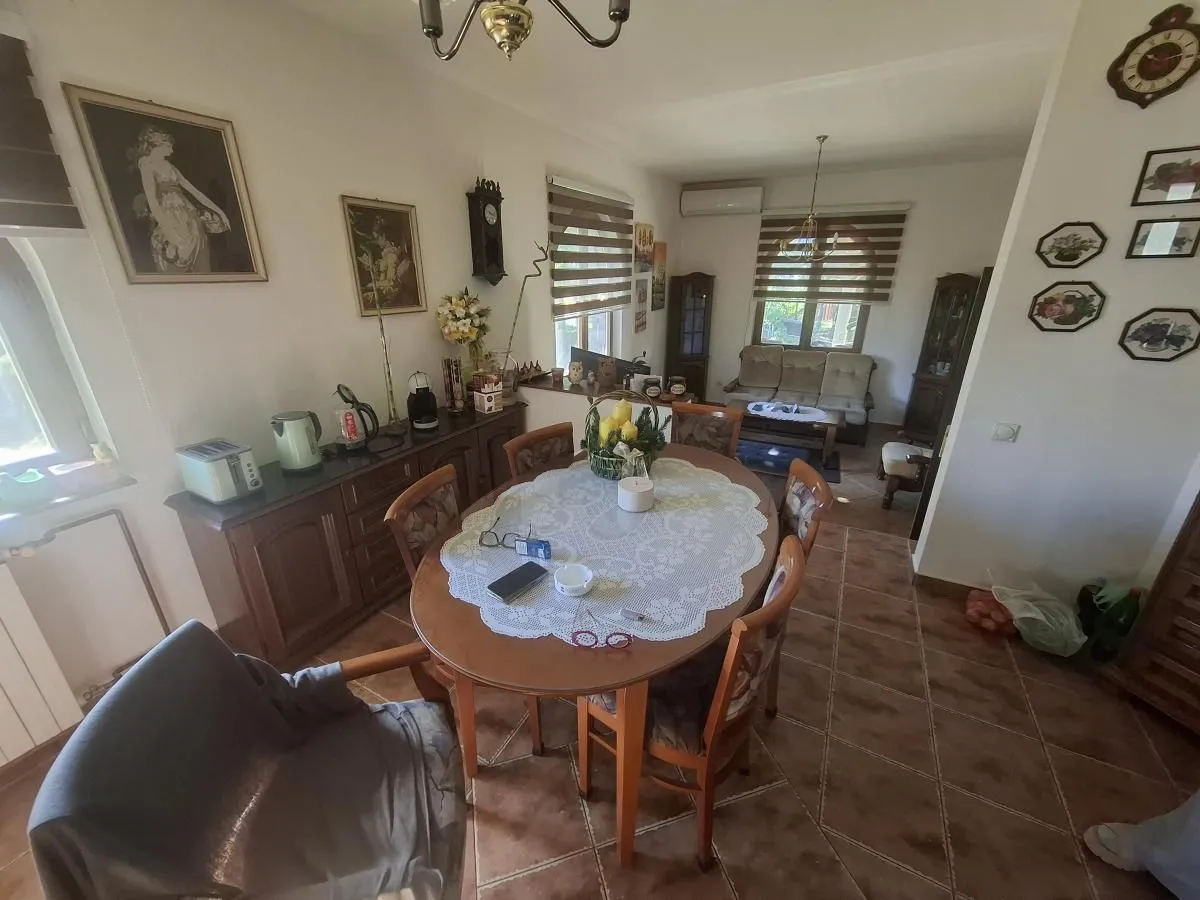 Trpezarija sa drvenim stolom i stolicama u okviru dnevnog boravka.