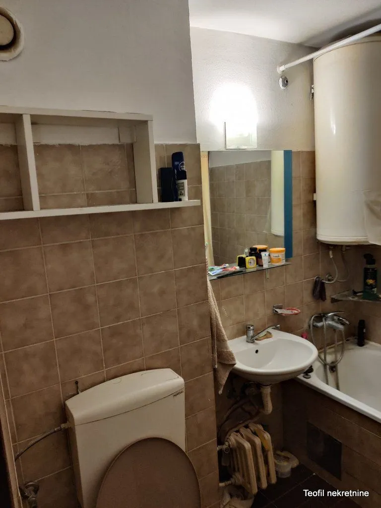 Manje kupatilo sa kadom, umivaonikom i wc šoljom obloženo keramičkim pločicama.