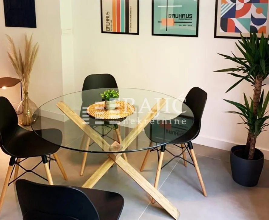 Dining area with a round glass table and black chairs.