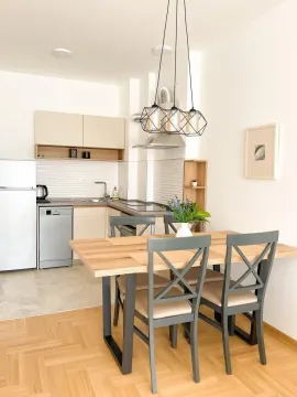 Dining area with a wooden table and a modern kitchen in the background. - image 7