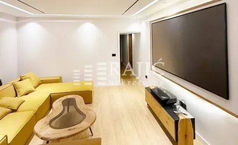 Modern living room with a yellow sofa and a large screen on the wall. - image 2