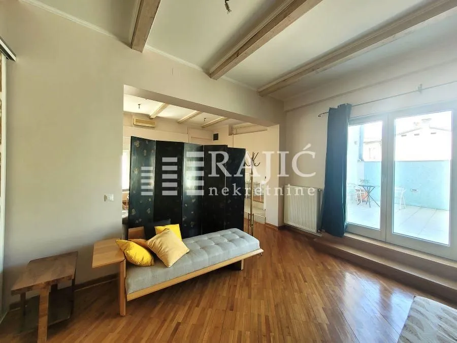 Living room with wooden flooring, seating furniture, and access to the terrace.