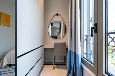 Small bedroom with a built-in wardrobe, a desk, and a mirror. - image 19