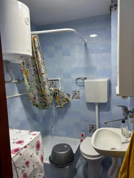 Manje kupatilo sa plavim pločicama, tuš kabinom i bojlerom. - image 10