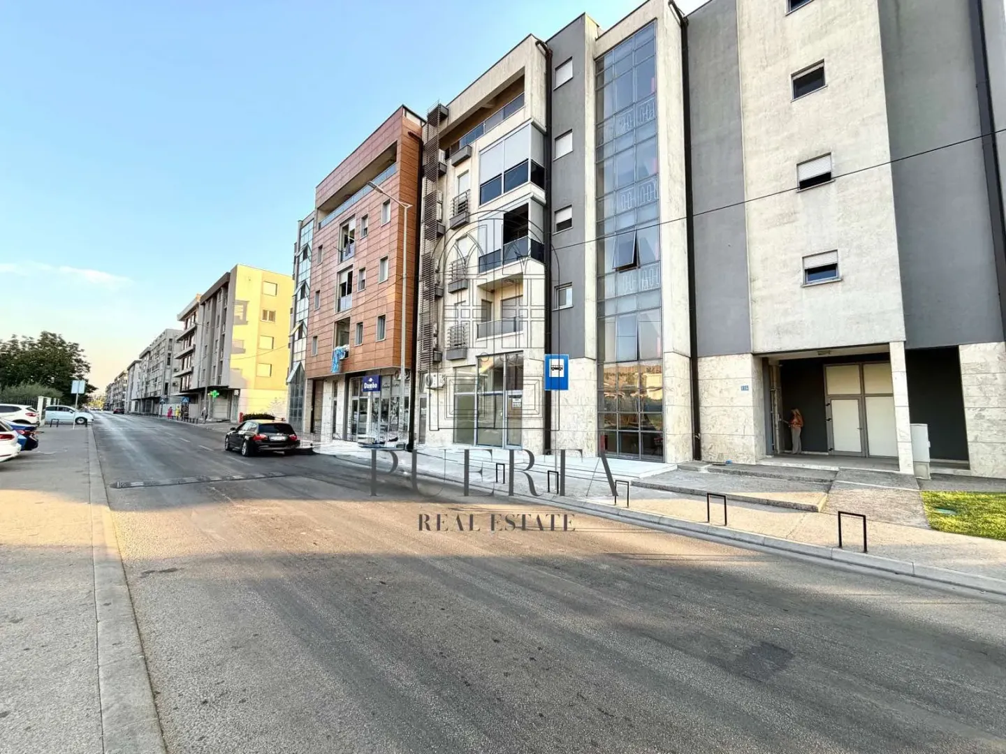 Pogled na spoljašnjost moderne stambene zgrade i ulicu ispred.