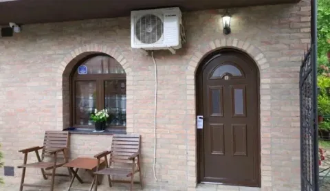 Fasada kuće sa ulaznim vratima, prozorom i drvenim stolicama ispred. - image 2