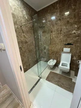 Bathroom lined with marble tiles featuring a walk-in shower, toilet, and bidet. - image 14