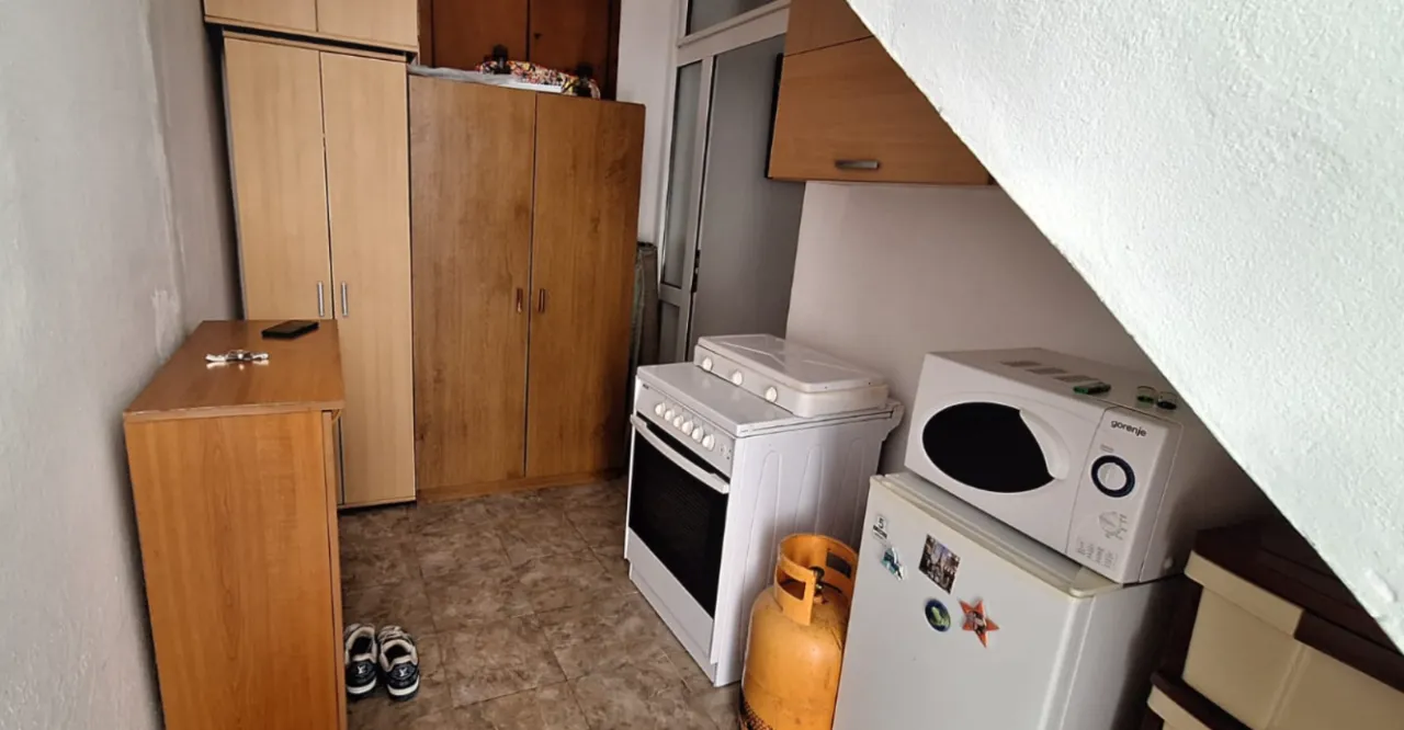 Manja kuhinja sa šporetom, frižiderom i drvenim ormarima.