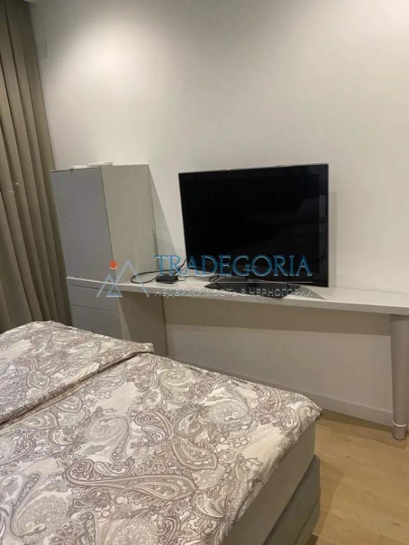 Spavaća soba sa krevetom, TV-om i komodom.