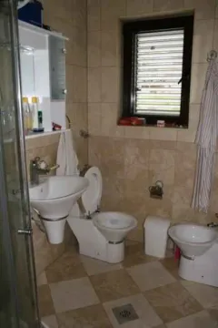 Kupatilo sa pločicama u toplim tonovima, lavaboom, bideom i toaletom. - image 25