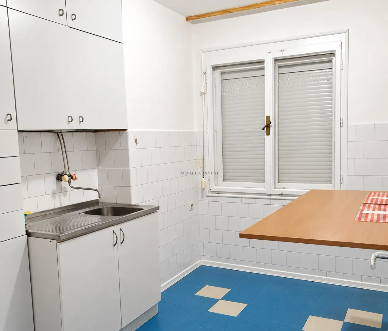 Kitchen with white cabinetry, a sink, and a wooden table by the window.