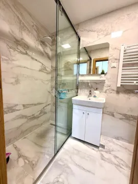 Modern bathroom with a walk-in shower lined with marble tiles. - image 10