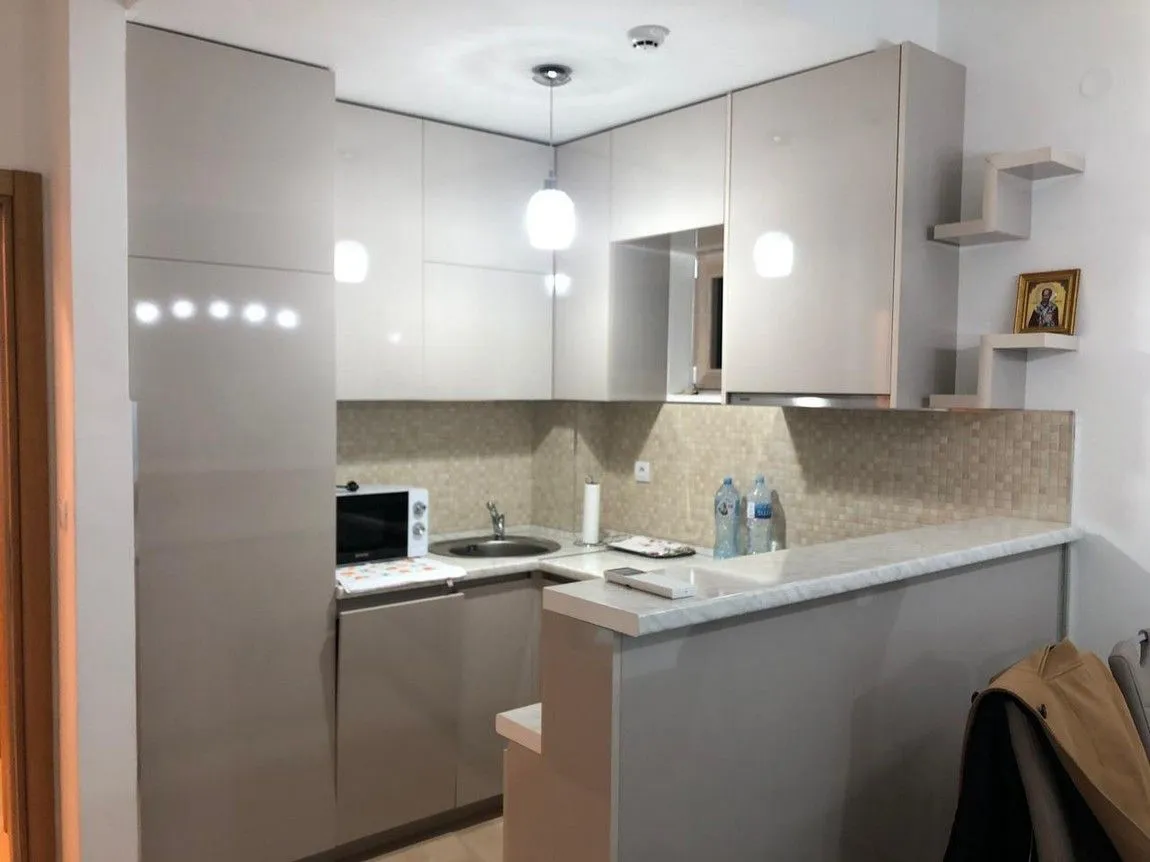 Manja opremljena kuhinja sa šankom i ugradnim elementima u svijetlim tonovima.