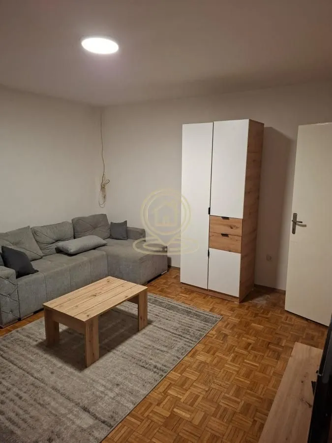 Dnevna soba sa ugaonom garniturom, stočićem i ormarom.