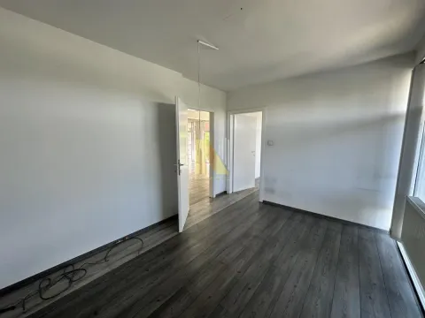 Empty room with dark laminate flooring and white walls. - image 9