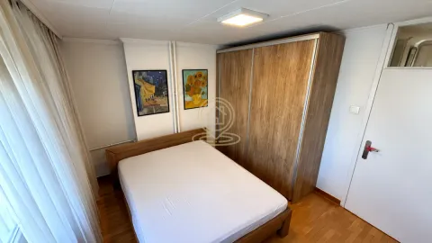 Nameštena spavaća soba sa bračnim krevetom, drvenim ormanom i slikama na zidu. - image 7