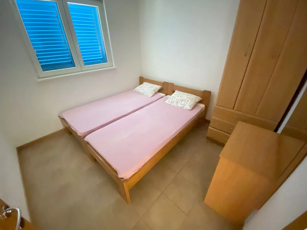 Namještena spavaća soba sa dva kreveta i ormarom.