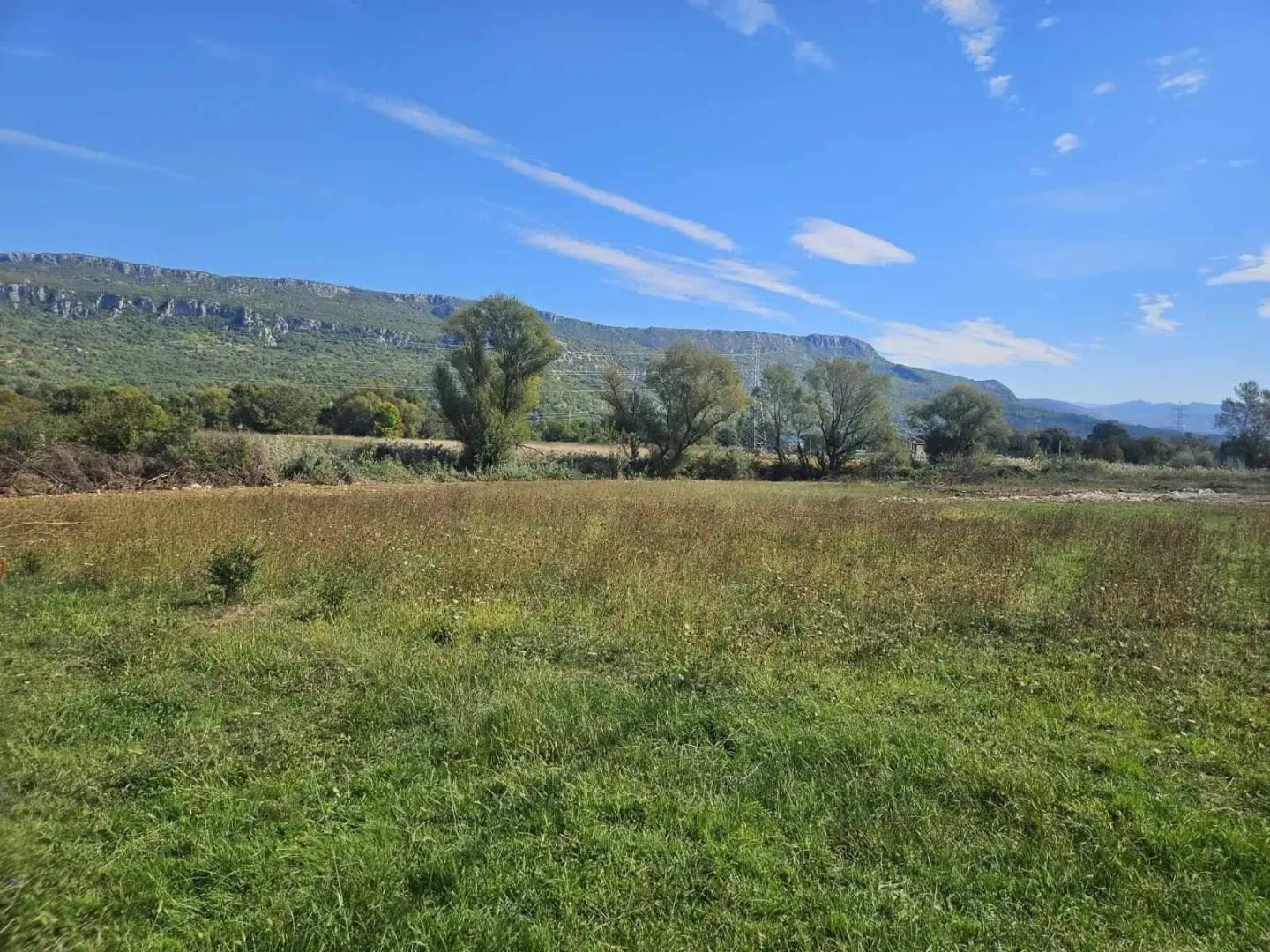 Prostran travnati plac sa pogledom na planine u daljini.
