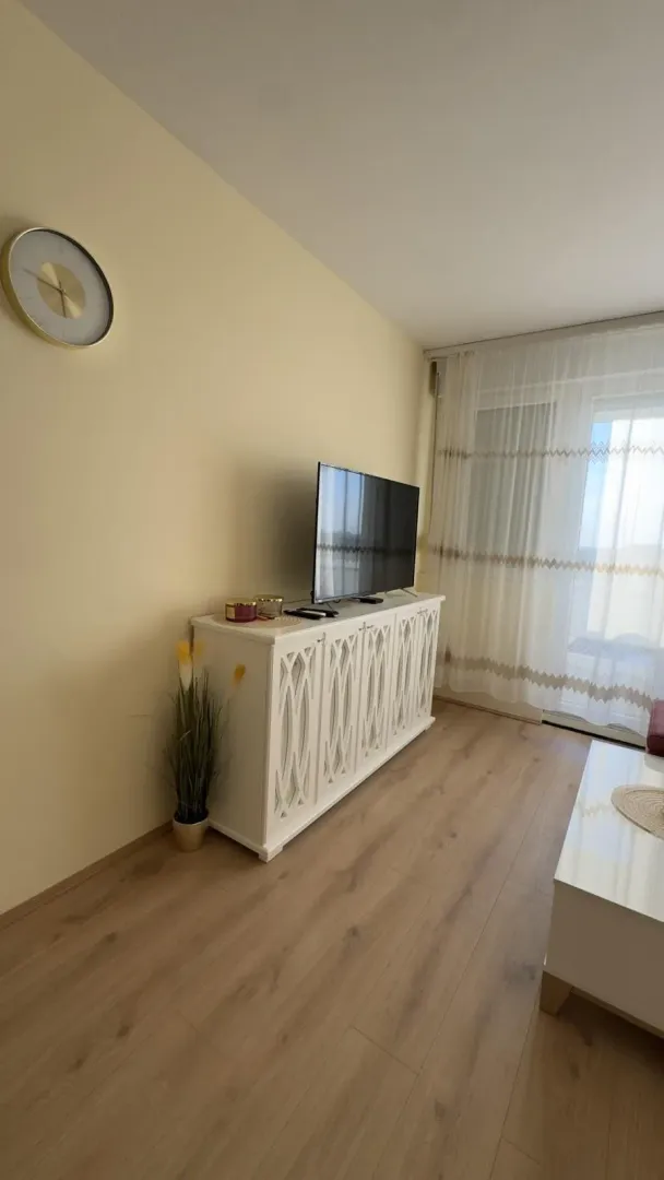 Dnevna soba sa televizorom na komodi i izlazom na terasu.