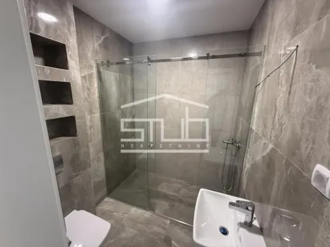 Moderno kupatilo sa tuš kabinom obloženom staklenim paravanom i mermernim pločicama. - image 13