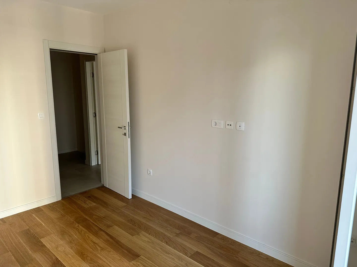 Empty room with wooden flooring and an open door.