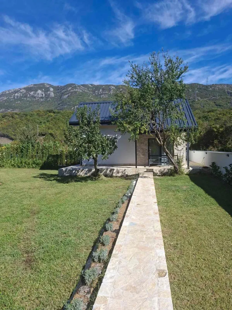 Exterior of the house with a landscaped yard, walkway, and mountain landscape in the background.