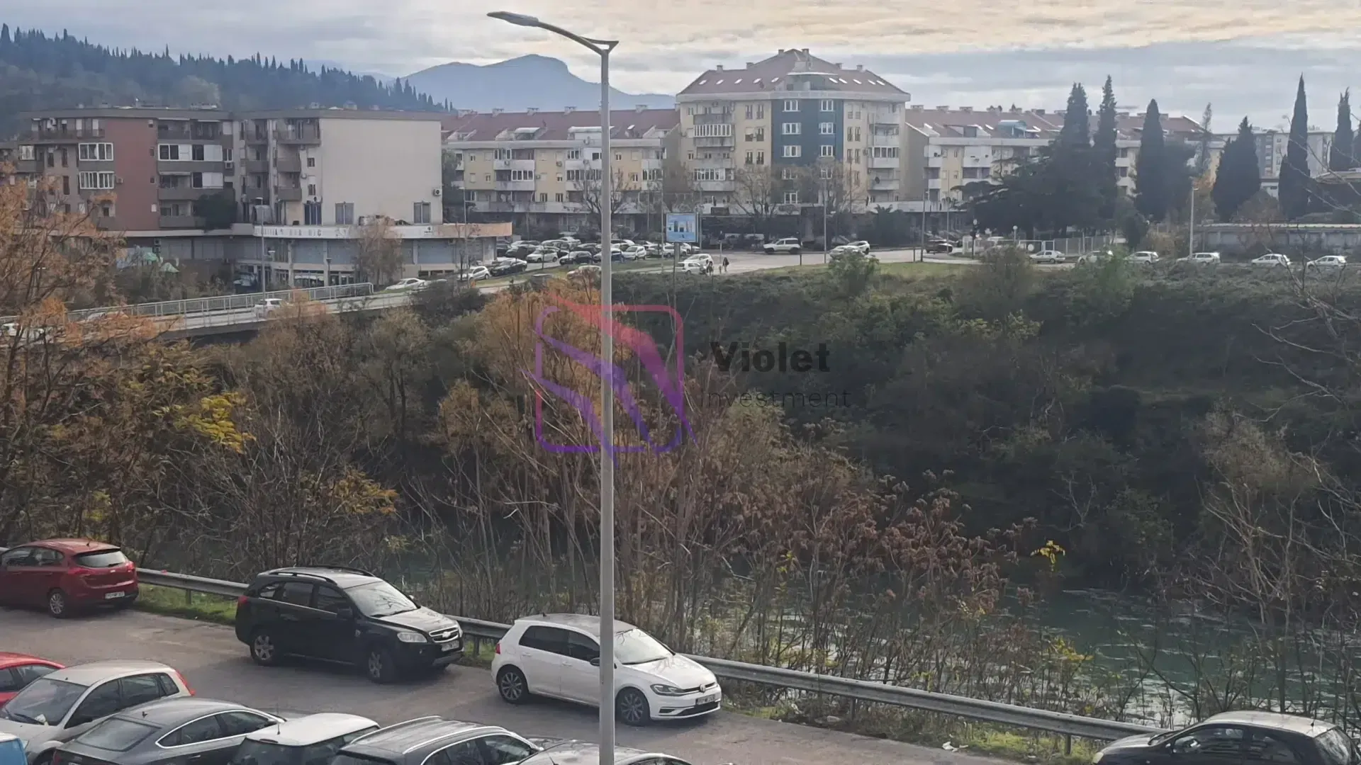 View from the window overlooking surrounding buildings, parking and nature.