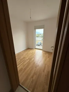 Prazna soba sa parketom i balkonskim vratima gledana sa vrata. - image 7