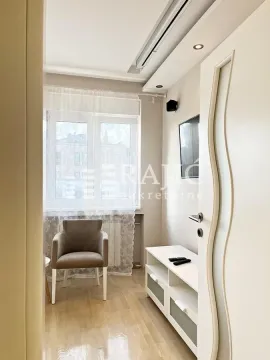 Small lit living room with an armchair, TV cabinet and a window. - image 17
