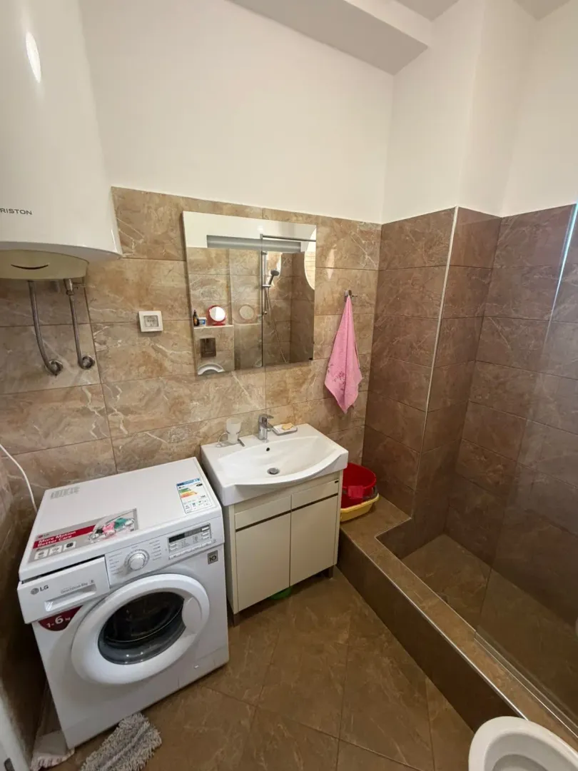 Bathroom with a sink, shower cabin, and washing machine.