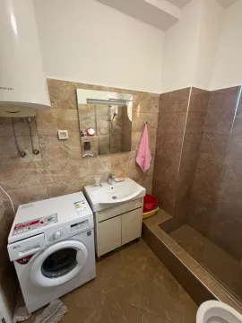 Bathroom with a sink, shower cabin, and washing machine. - image 11