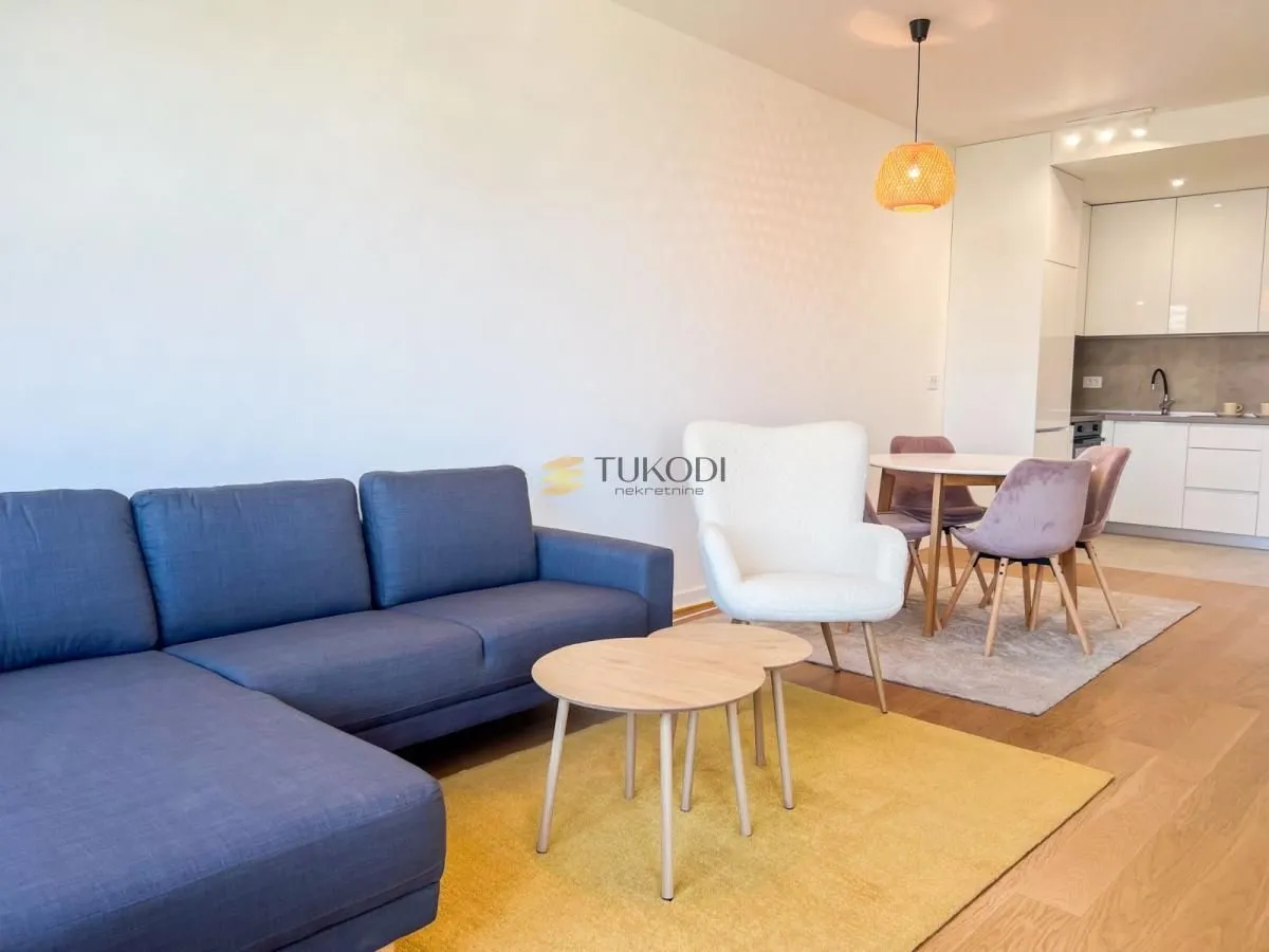 Living room with a sofa and a dining area connected to the kitchen.