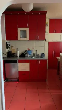 Kuhinja sa crvenim elementima i keramičkim pločicama na podu. - image 6