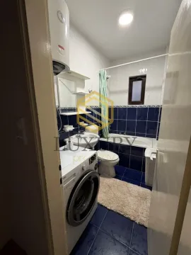 Small bathroom with a bathtub, washbasin, washing machine, and blue tiles. - image 8