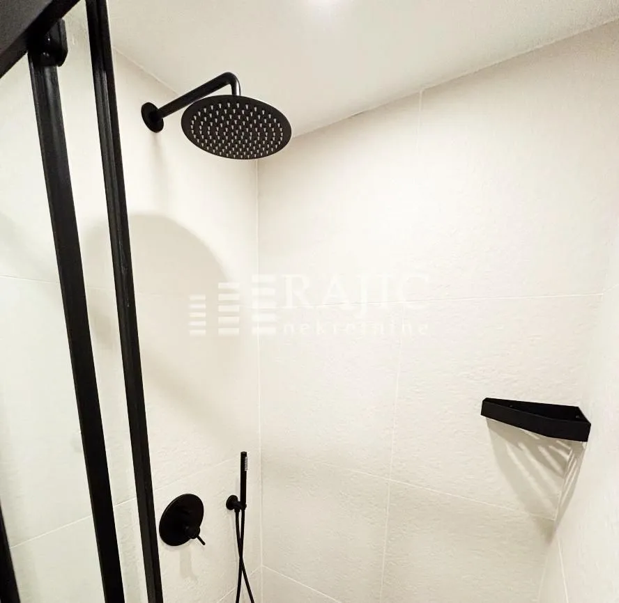 Modernly equipped bathroom with a walk-in shower and black fixtures.