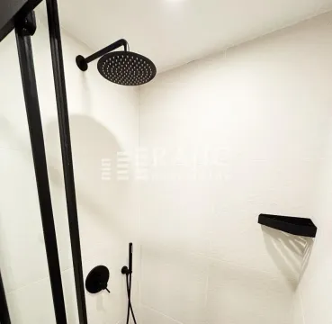 Modernly equipped bathroom with a walk-in shower and black fixtures. - image 13