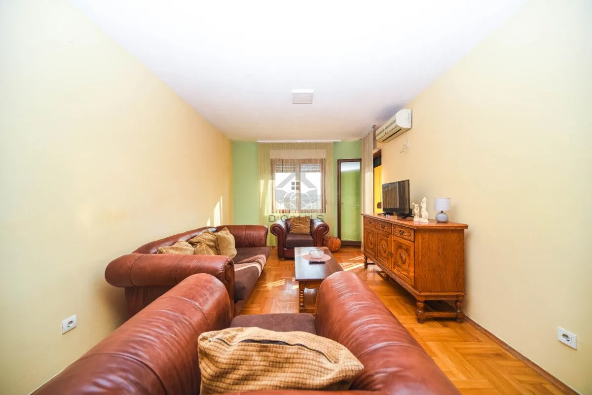 Living room with leather sofas, a wooden cabinet, and a TV.