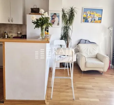 Living room with a bar counter and kitchen in the background. - image 7
