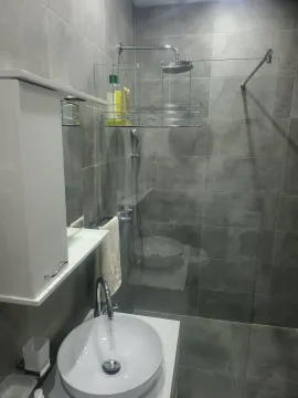 Modern bathroom with grey tiles, a walk-in shower, and a white sink. - image 20