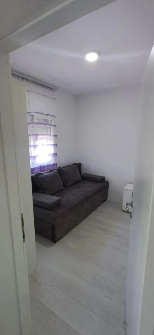Smaller living room with a dark sofa and light laminate flooring.