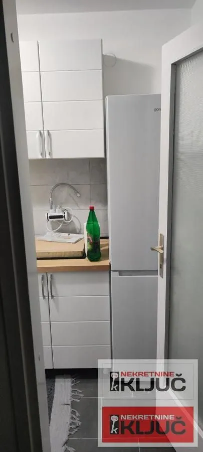 Manja kuhinja sa belim elementima i frižiderom.