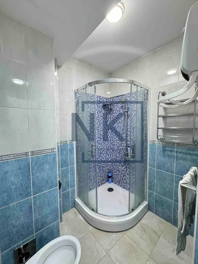 Kupatilo sa tuš kabinom, WC šoljom i pločicama u plavim tonovima.