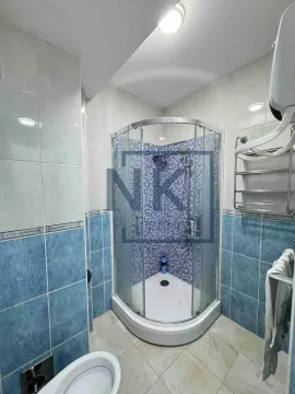 Kupatilo sa tuš kabinom, WC šoljom i pločicama u plavim tonovima. - image 12