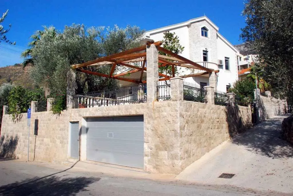 Pogled na spoljašnjost kuće sa garažom i terasom.
