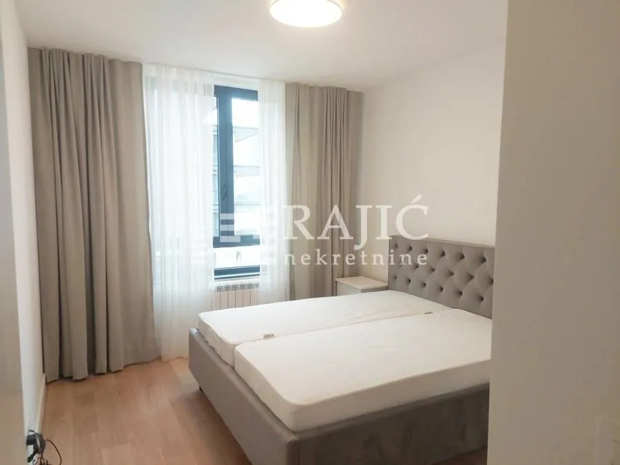 Bedroom with a large double bed and a window with curtains.