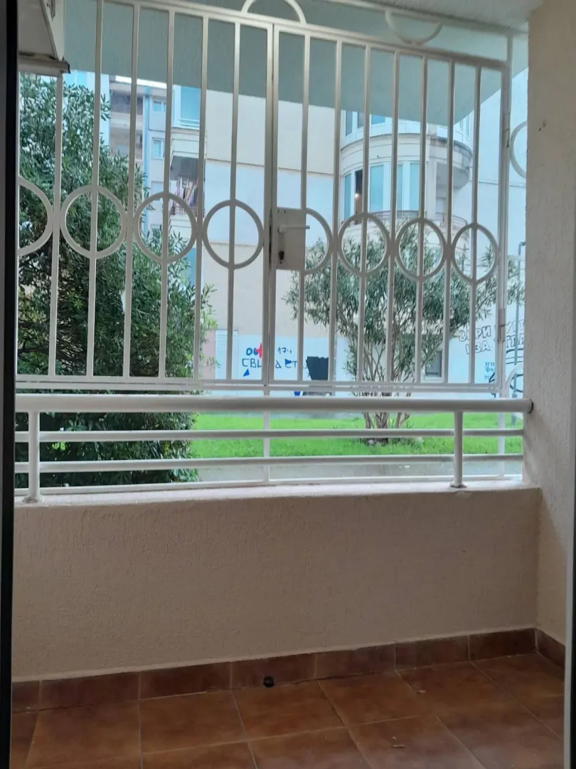 Balkon sa zaštitnom rešetkom i pogledom na dvorište.