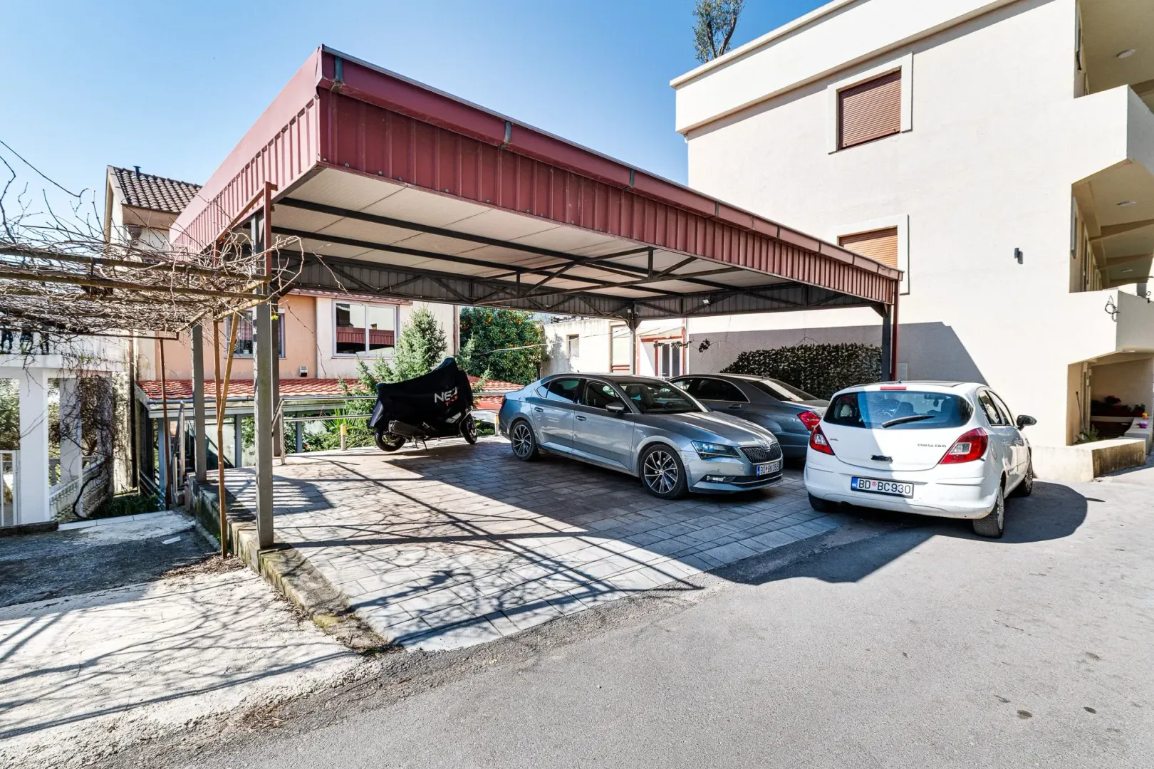 Natkriveni parking prostor sa parkiranim automobilima ispred zgrade.