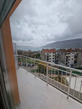 Balkon sa metalnom ogradom i pogledom na more i okolne zgrade. - image 11