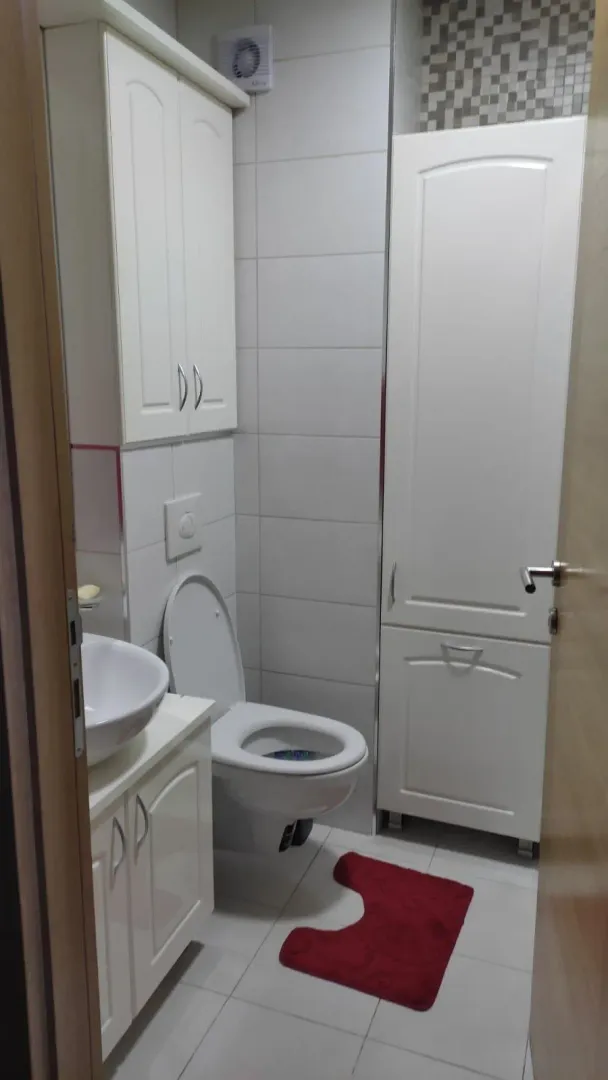 Manje kupatilo sa bijelim namještajem, umivaonikom i toaletom.